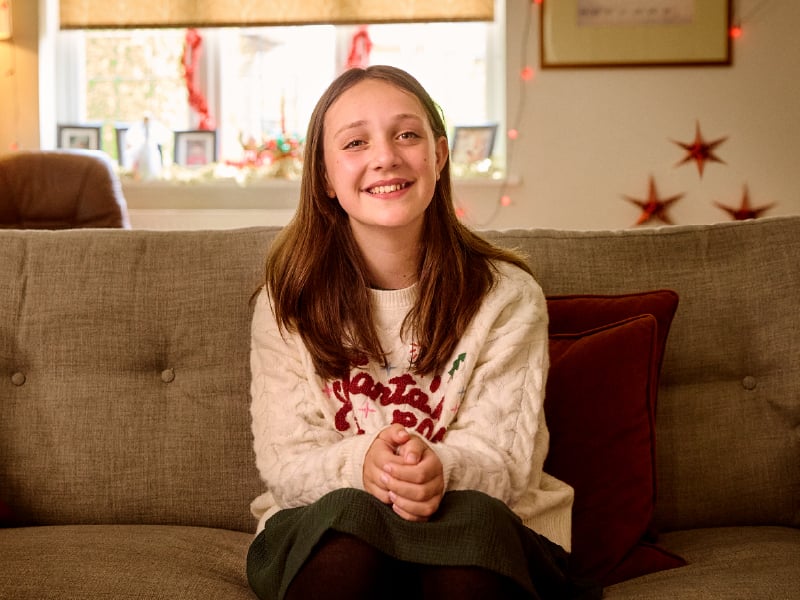 Bea, sat on a sofa smiling