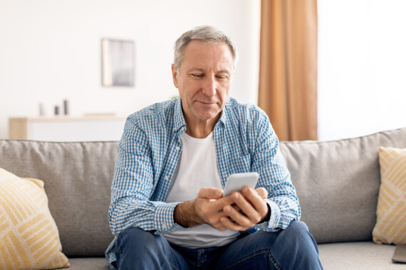 Seated man looking down at his mobile phone
