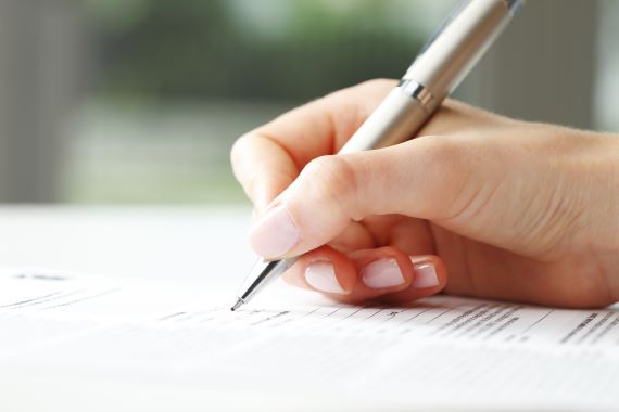 Someone filling in a form using a pen