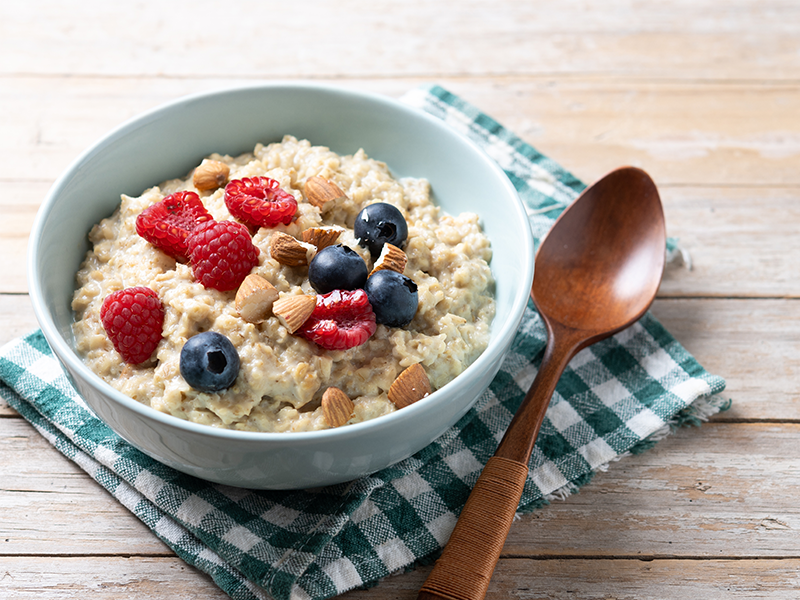 A bowl of porridge with berries and nuts on top.