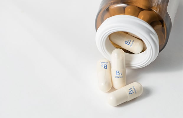 A bottle of pills each labelled with vitamin B3 spilling onto a table.