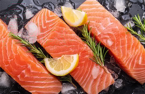 Three salmon fillets with lemon, ice and rosemary.