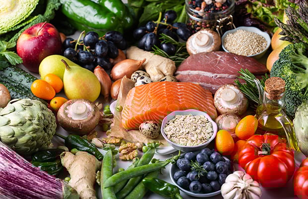A range of fruits, vegetables, fish, meat and grains on a table.