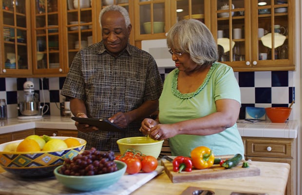 A couple cooking a healthy meal together in a kitchen.