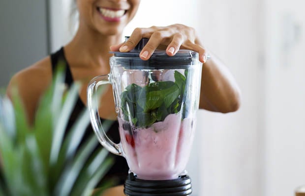 Woman making a berry and spinach smoothie