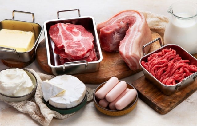 High saturated fat foods, including red meat, cheese and butter, arrange on a table