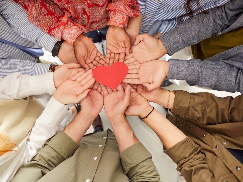 A group of hands holding a heart